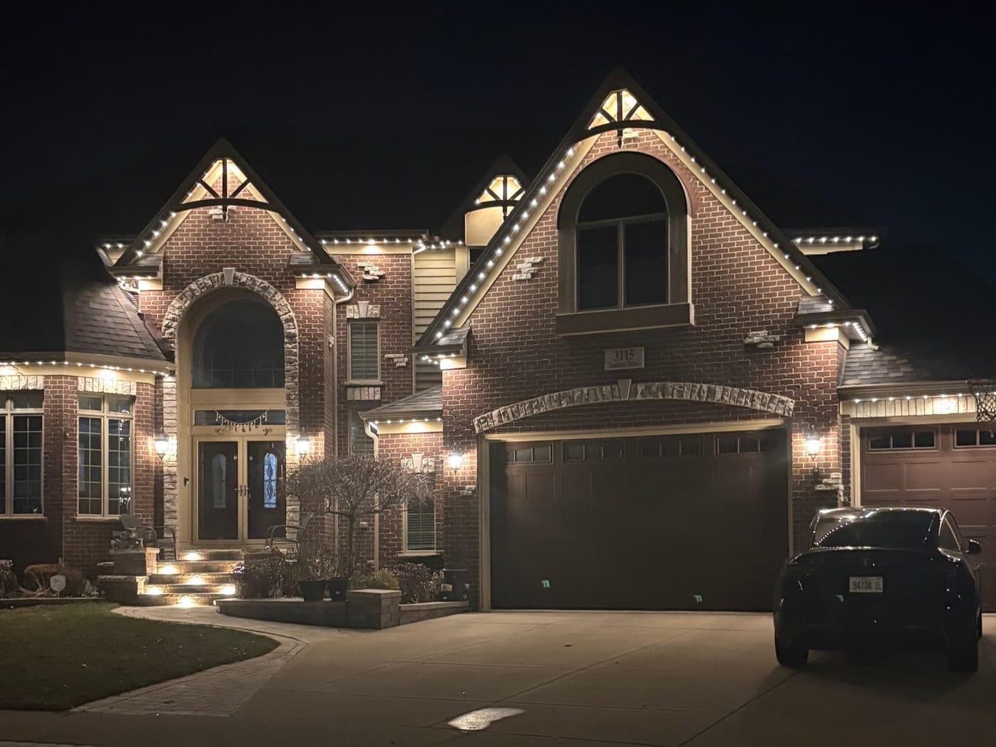 Brick colonial home in Naperville, IL with permanent lighting outlining an arched entryway